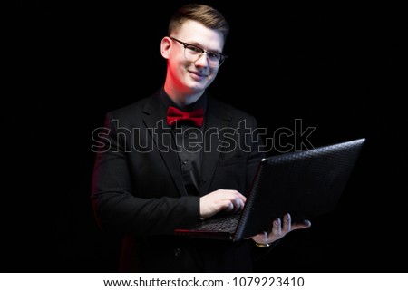 Portrait of confident handsome ambitious happy elegant responsible businessman working on his laptop on black background