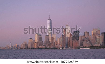 ESTABLISHING SHOT: Iconic contemporary glassy skyscrapers lit up against stunning purple-pink sky of a dawn in Lower Manhattan, New York City. Famous NYC financial district skyline at magical sunrise