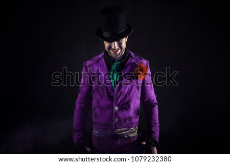A mysterious man in a suit, with a cane, in a cylinder. Dark background. Scary and sinister. Joker, Halloween costume