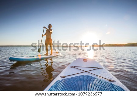 Standup paddler at the lake during sunset Royalty-Free Stock Photo #1079236577