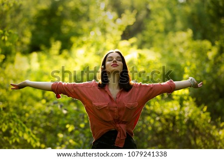 Young woman spreading arms to the sky. Outdoor summer day. Meditation and freedom concept Royalty-Free Stock Photo #1079241338