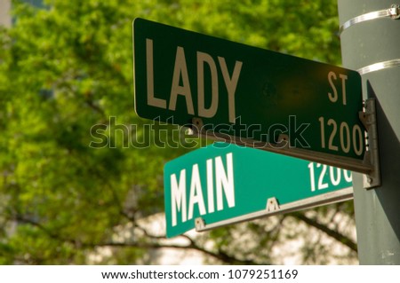 Green and white street signs on light pole displaying the names Main Street and Lady Street