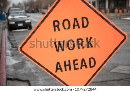 Tilted roadside orange road work ahead sign