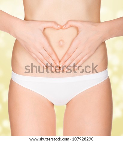 Hands on female belly, golden blurred background