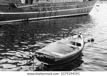 Yachts docked at the port of Malta. A shabby old boat among the luxury ships. Black and white picture