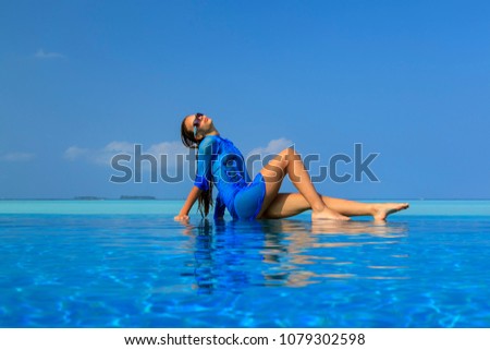 The Maldives. Paradise rest. Beautiful seascape. Place for relaxation, concept of blue color. young girl in blue wet dress on the edge of the pool and blue sky background.