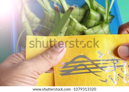 Giving and receiving money packet during Eid Fitri. Arabic character means Eid Mubarak