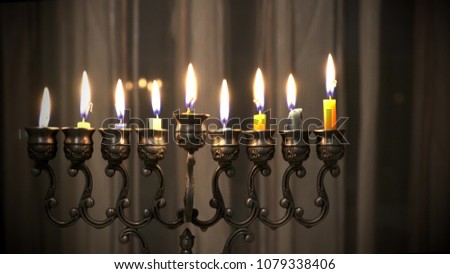 Last eighth day of the Jewish holiday Hanukkah. Nine Hanukkah candles are burning on light curtain background. 