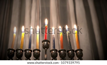 Last eighth day of the Jewish holiday Hanukkah. Nine Hanukkah candles are burning on light curtain background. Selective focus. 