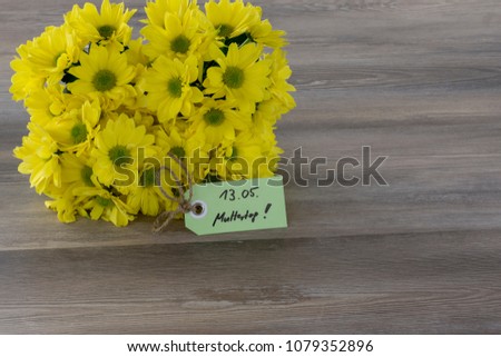 Beautiful bouquet of tulips and card on wooden background. Label with German text 13 Mai Muttertag!, translate 13 May Mother's Day.