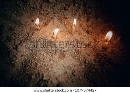 The candle was lit. and embroidered in a pot of sand.