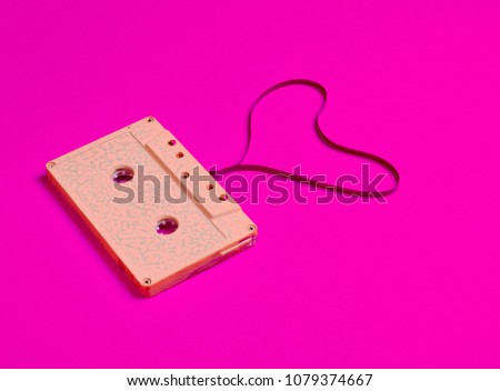Heart shape from audio cassette tape on pink paper background, top view. Hipster Love.
