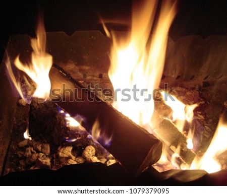 Burning wood in brazier. Dying embers. Smoldering firewood, glowing logs, closeup. Campfire flaming soft glowing flame.