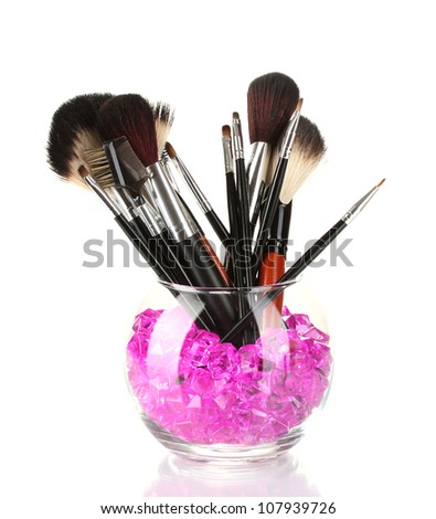 Make-up brushes in a bowl with stones isolated on white