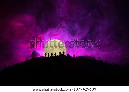 Scary view crowd of zombies on hill with spooky cloudy sky with fog and rising full moon. Silhouette group of zombie walking under full moon. Halloween concept.