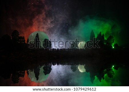 Silhouette of a large crowd of people in forest at night watching at rising big full Moon. Decorated background with night sky with stars, moon and space elements. Selective focus. Surreal world