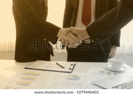 Businessman and partner shaking hands in office with vintage filter
