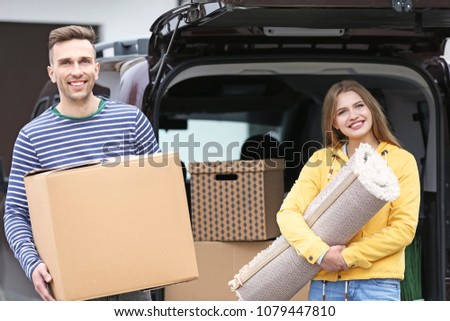 Young couple unloading their car on moving day