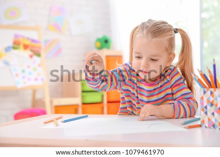 Little cute girl drawing at table indoors