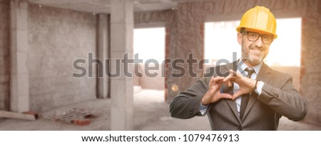 Senior architect or engineer happy showing love with hands in heart shape expressing healthy and marriage symbol at unfinished building