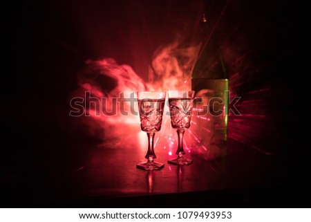 Two glasses of Vodka with bottle on dark foggy club style background with glowing lights (Laser, Stobe) Multi colored. Club drinks theme decoration. Empty space. Selective focus