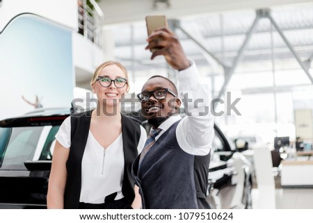 Business girl with African man doing a selfie in front of the car