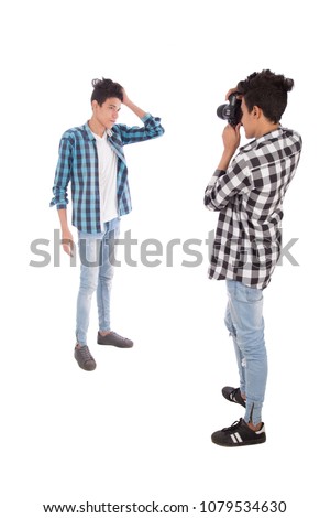 Full-length shot of a brother holding the camera and taking photos to his brother, isolated on a white background.