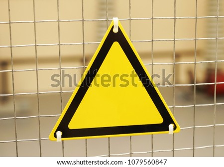 Empty triangular yellow sign on a mesh fence.