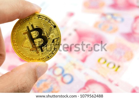 Close up man hand holding golden bitcoin over blurred one hundred Chinese yuan banknotes background. Cryptocurrency, digital currency with China money bills.