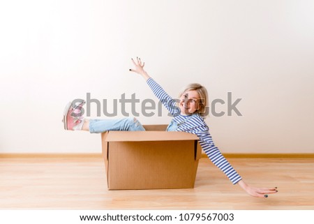 Photo of young woman sitting in cardboard box