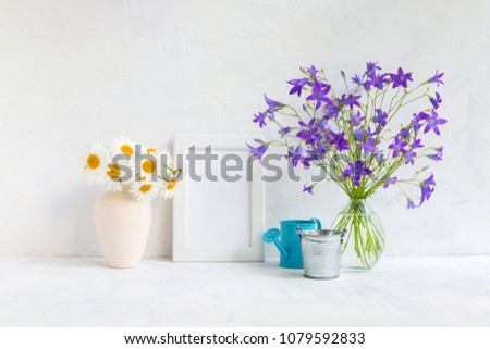 Mockup with a white frame and summer flowers in a vase on a light background
