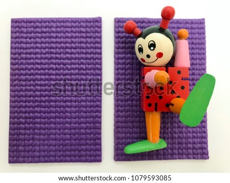 Ladybird on a rug for yoga and next to the left is an empty purple yoga mat and fitness