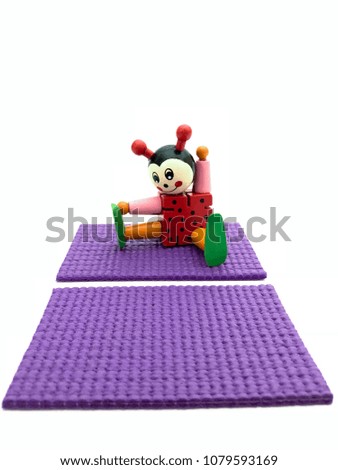 A ladybug sits on a fitness mat next to another empty purple yoga mat in the foreground