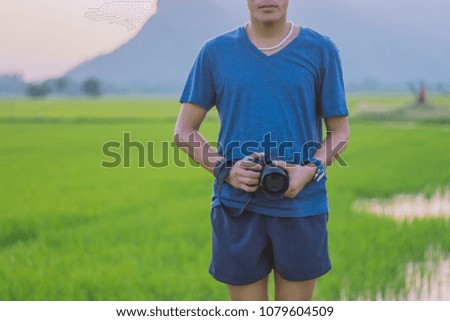 Young man practicing landscape photography before sunset at rice field.