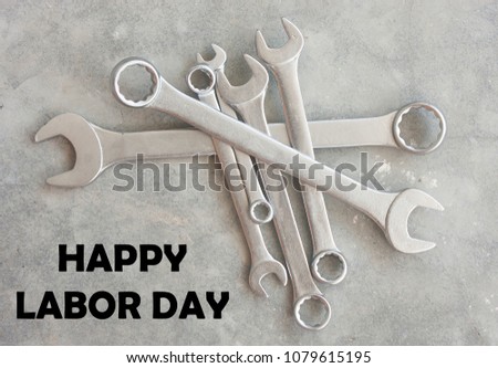 Wrench with word happy labor day isolated on concrete floor background