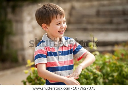 Happy cute Caucasian kid playing with water fountain in the public park.