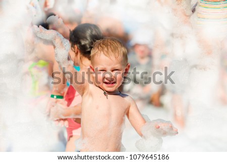 Foam Party on the beach. Baby boy having fun and dancing in a foam.