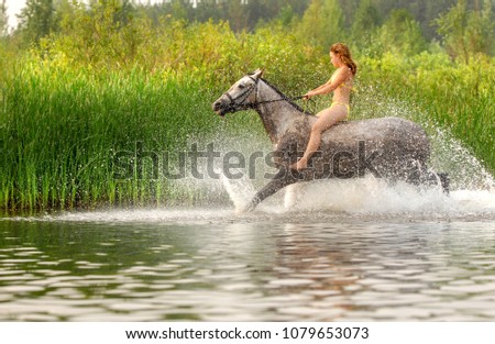 Summer, river. A girl in a swimsuit jumps on a horse