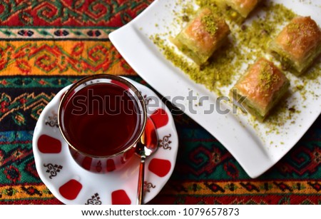 Top view of a set of Turkish afternoon tea which consists of Turkish black tea and pistachio baklava on a traditional table cloth, dessert and drink
