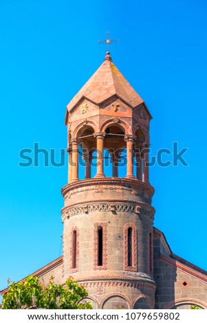 High cylindrical bell tower of St.Mesrop Mashtots Church in the village of Oshakan the background of a cloudy spring sky