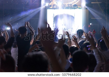 silhouettes of concert crowd in front of bright stage lights in China