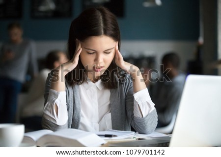 Stressed female student having headache touching temples preparing for test in cafe, frustrated millennial girl feels nervous or tired, afraid of exam failure, suffering from anxiety or panic attack Royalty-Free Stock Photo #1079701142