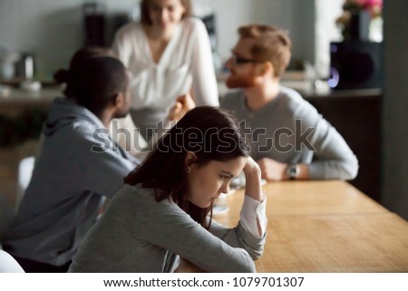 Sad frustrated young girl feeling lonely sitting alone at cafe table, upset social outcast or loner teenager suffering from low self esteem complex, unfair attitude or discrimination among friends Royalty-Free Stock Photo #1079701307