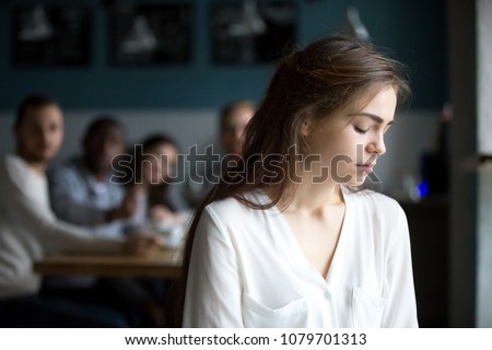 Sad young woman avoiding ignoring bad friends suffering from gossiping, bullying, unfair attitude or discrimination, frustrated millennial girl feeling upset, hurt and offended sitting alone in cafe Royalty-Free Stock Photo #1079701313