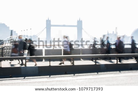 London, UK. Blurred image of office workers crossing the London bridge in early morning on the way to the City of London. Tower bridge at the background. Rush hours
