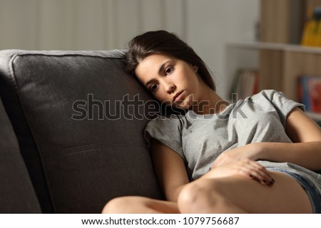 Sad teen looking away sitting on a couch in the living room at home Royalty-Free Stock Photo #1079756687