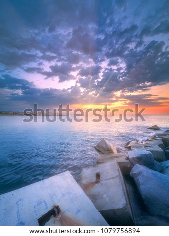 Barceloneta Beach in Barcelona with rocky coastline and colorful sky during violet sunrise, Spain