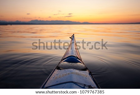 Bow of sea kayak at sunset pointed at Bainbridge Island and the Olympic Mountains, Puget Sound, Seattle, WA USA Royalty-Free Stock Photo #1079767385