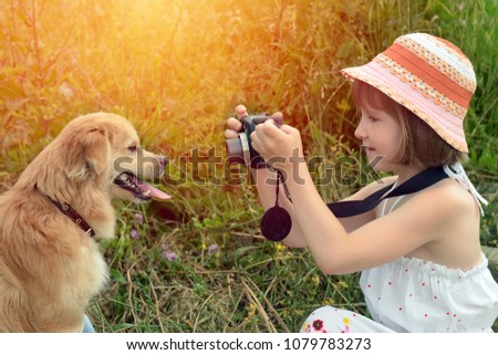 Little girl photographer taking pictures of a dog in nature.