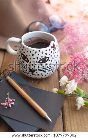 Black fragrant coffee, flowers, hat and glasses. Good morning, bright sunny colors. Women's accessories and notepad with a pen.
